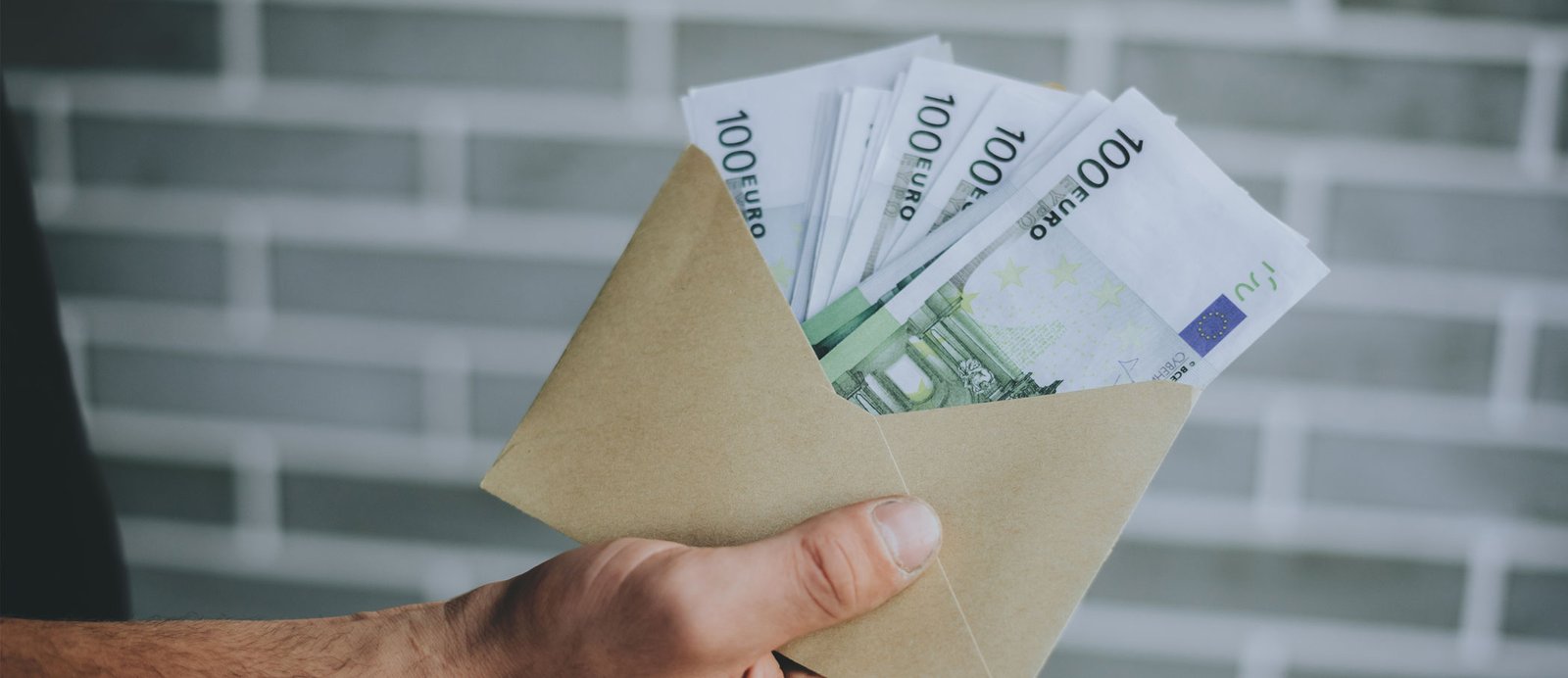 Hombre sosteniendo un sobre lleno de billetes, simbolizando el cobro del anticipo editorial como adelanto de las futuras regalías.