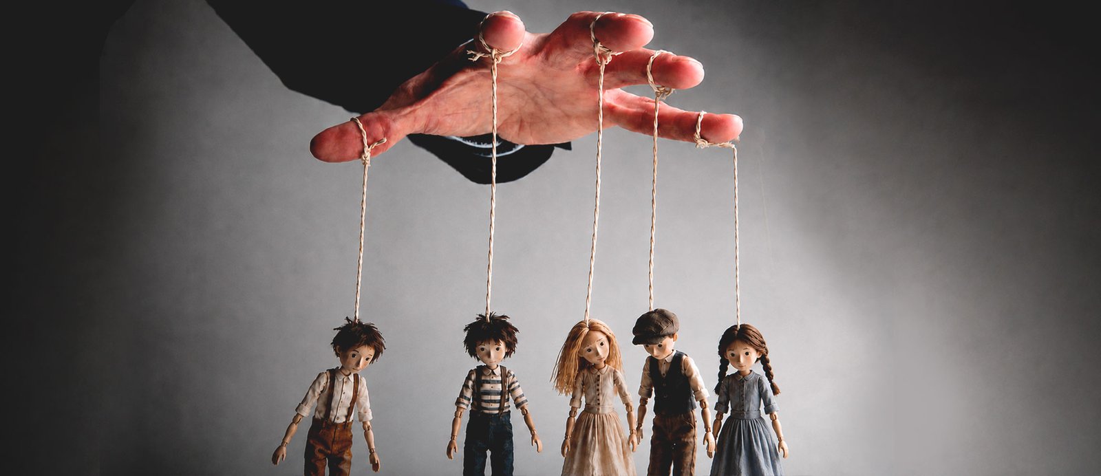 Del lector hipnotizado al ojo clínico: diseccionando el truco del ilusionista.. Una mano humana en primer plano controlando los hilos de cinco pequeñas marionetas de madera, representando la estrategia del autor para manipular la percepción del lector.