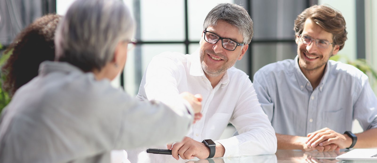 Varios hombres en una sala de negocios, cerrando el trato con la firma del contrato de adaptación audiovisual.