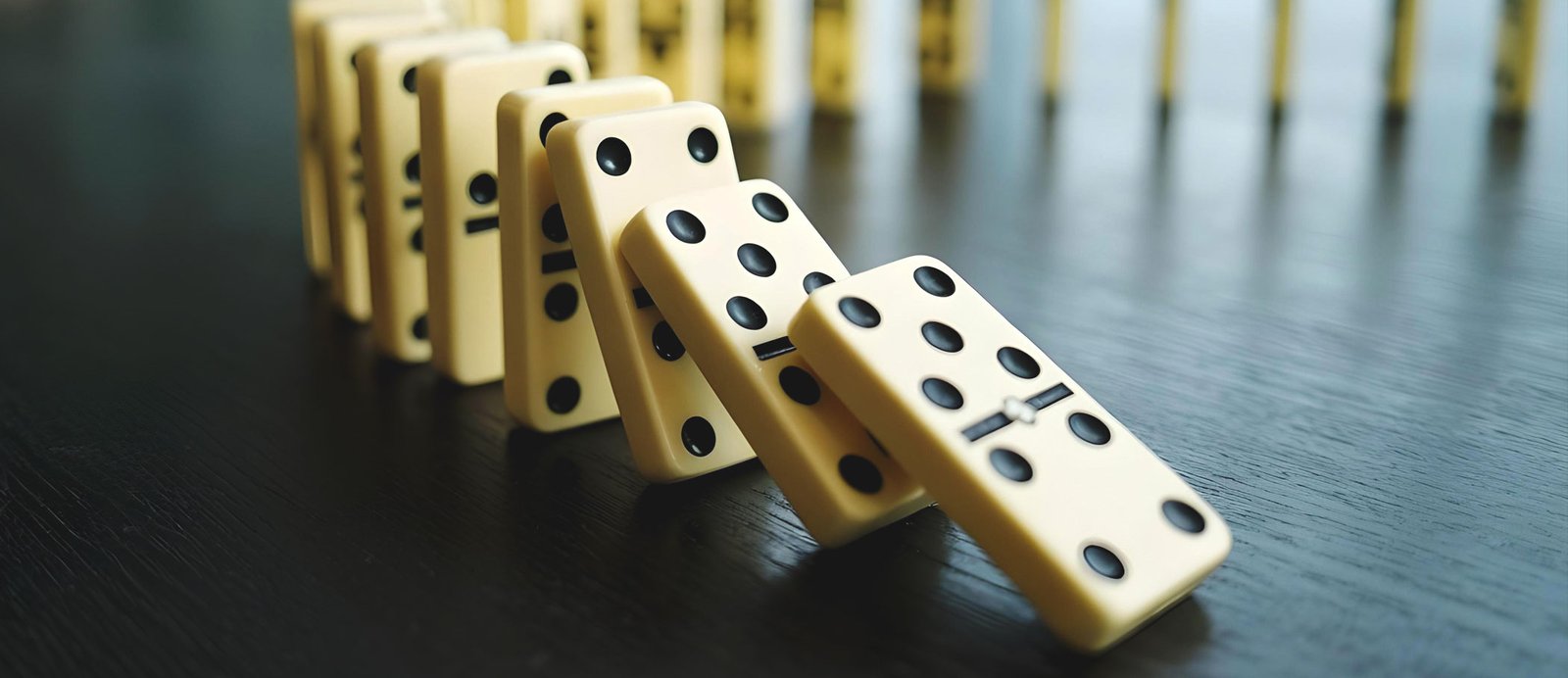 Vender primero en mercados pequeños ayuda a conquistar después los grandes mercados. Fichas de dominó cayendo sobre un mapa, ilustrando la estrategia de venta internacional escalonada.