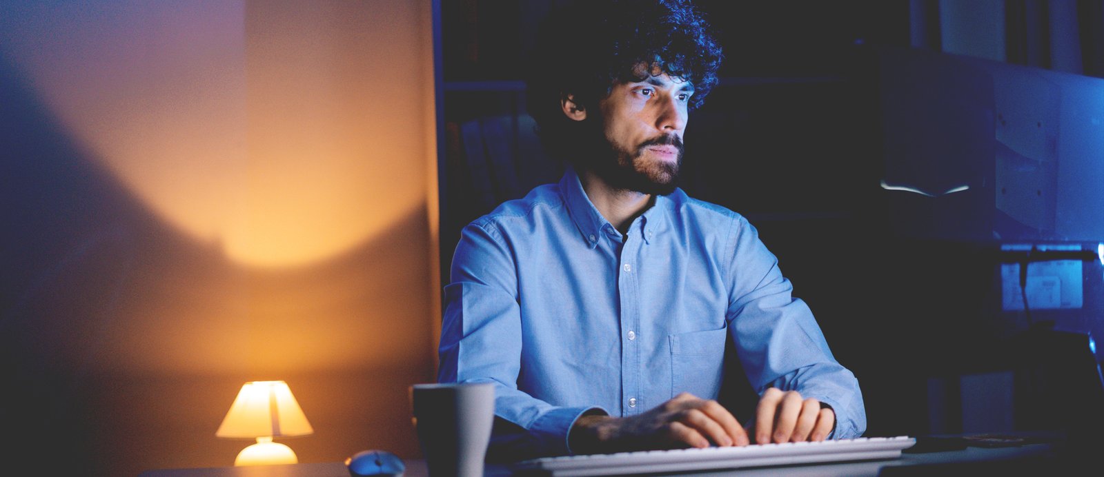 Autor independiente trabajando de noche frente a su ordenador, adoptando la mentalidad de CEO para planificar la estrategia de su libro.