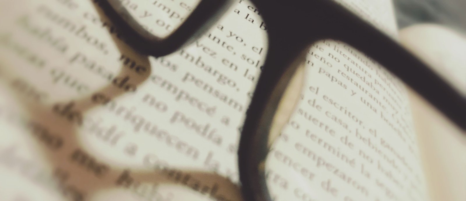 Unas gafas de lectura reposando sobre un manuscrito, simbolizando el riguroso filtro y la evaluación técnica que realizan las editoriales.