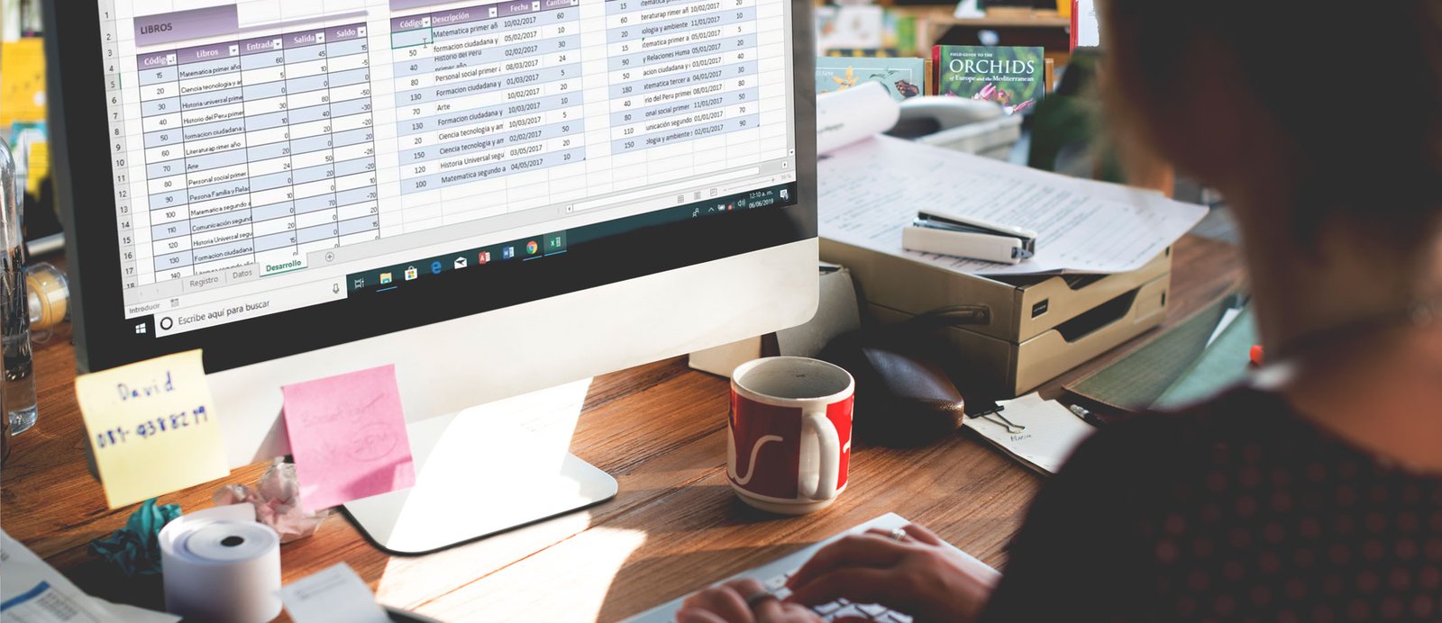 El ISBN identifica a tu libro y permite que los libreros puedan acceder a sus metadatos. Dependienta de una librería buscando un libro en su ordenador, demostrando cómo los metadatos asociados a un ISBN son utilizados en la cadena comercial.